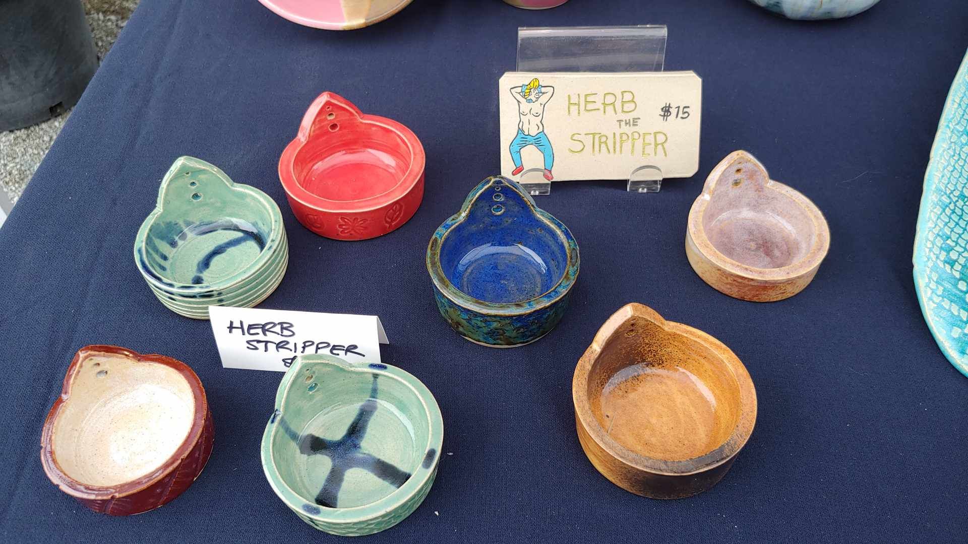 Herb the Stripper, advertising Em's herb strippers at a market.